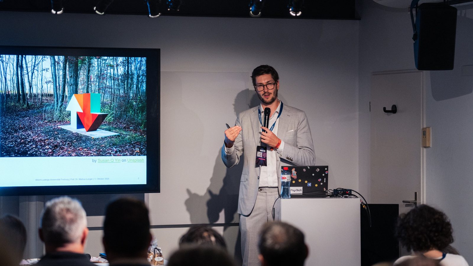 Markus Langer hält einen Vortrag beim AI+X Summit in Zürich, links eine Präsentationsfolie